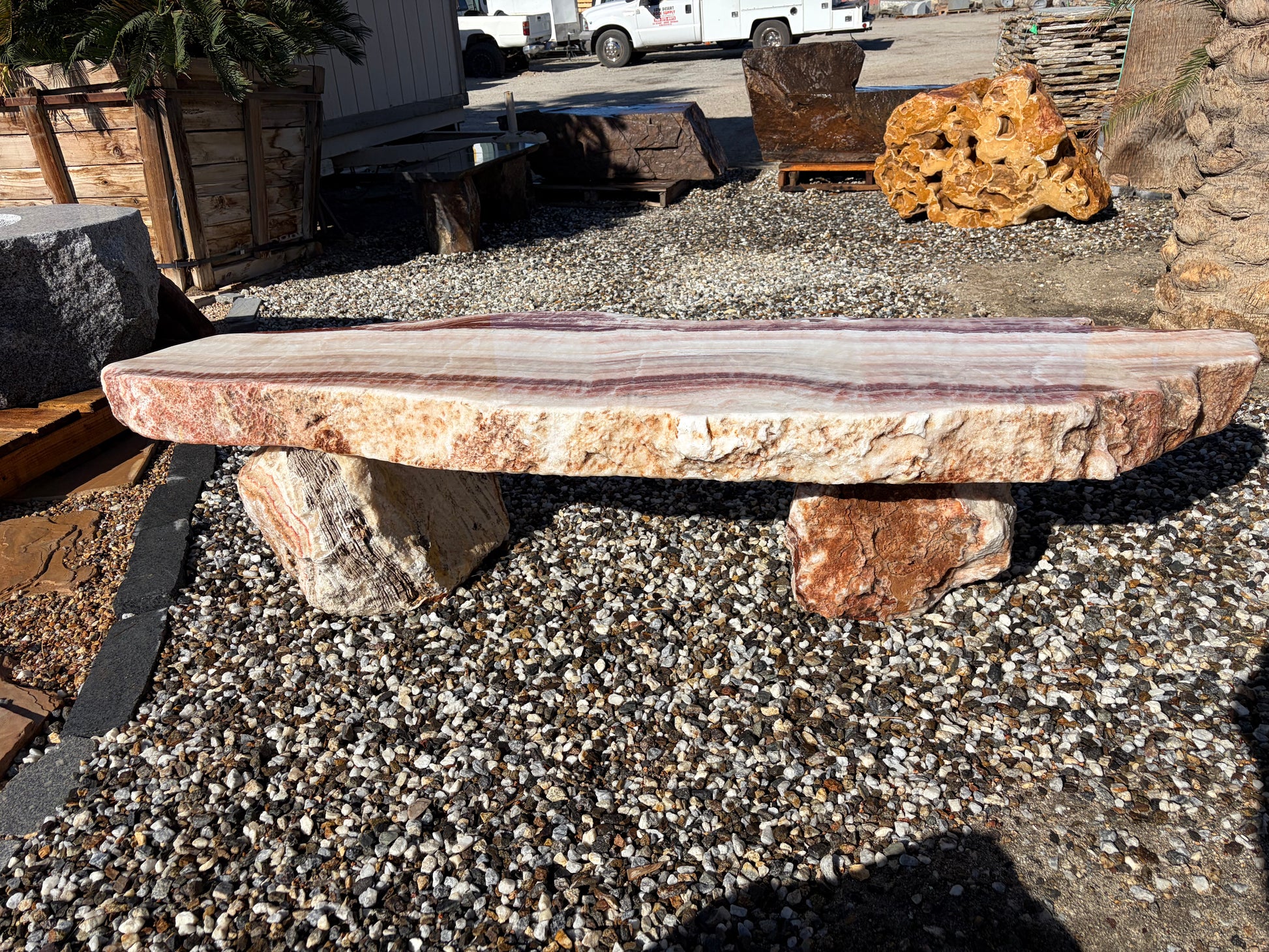 Natural onyx stone bench with unique color variations and polished surface for outdoor gardens and landscaping.