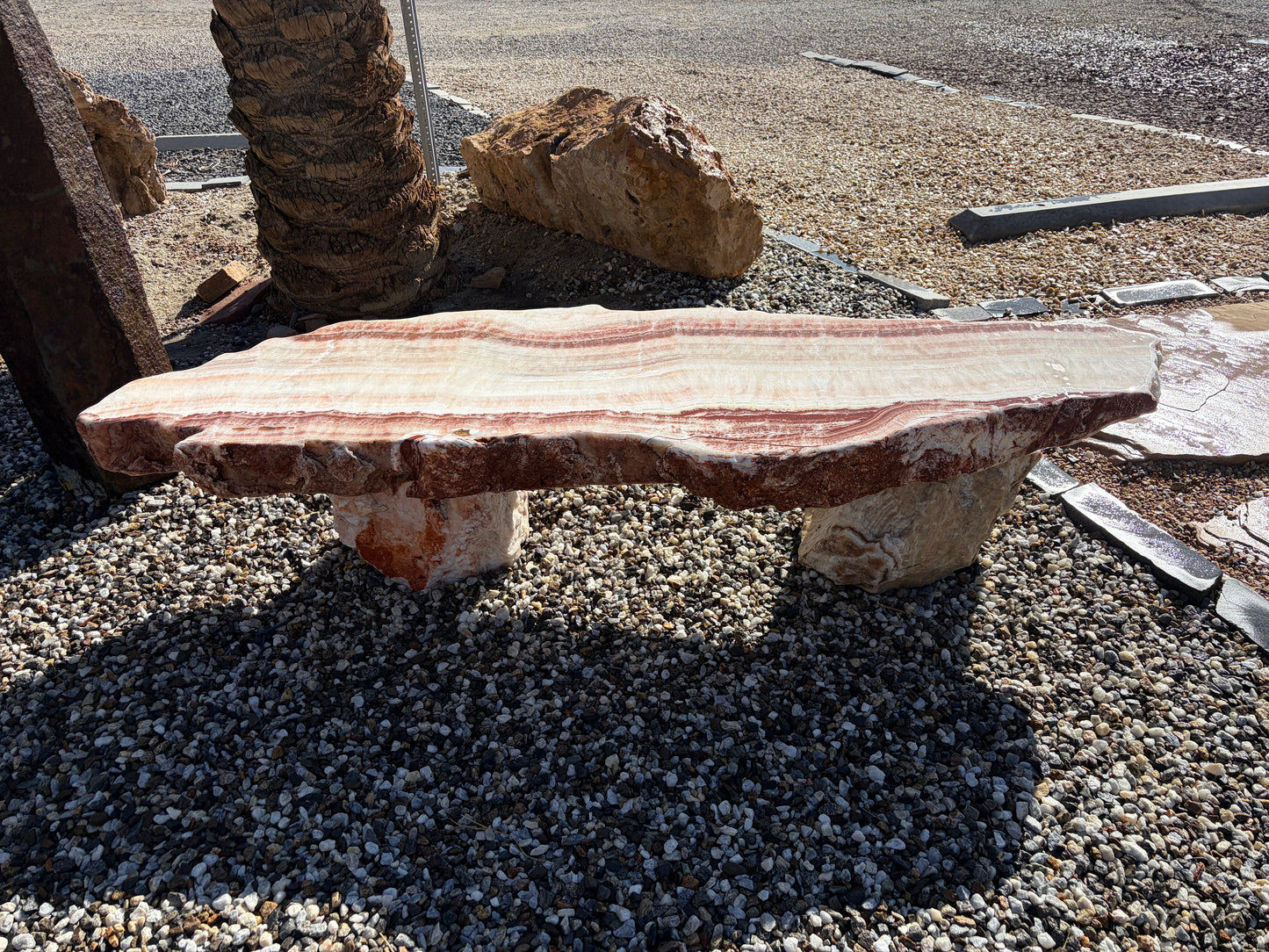 Natural onyx stone bench with unique color variations and polished surface for outdoor gardens and landscaping.