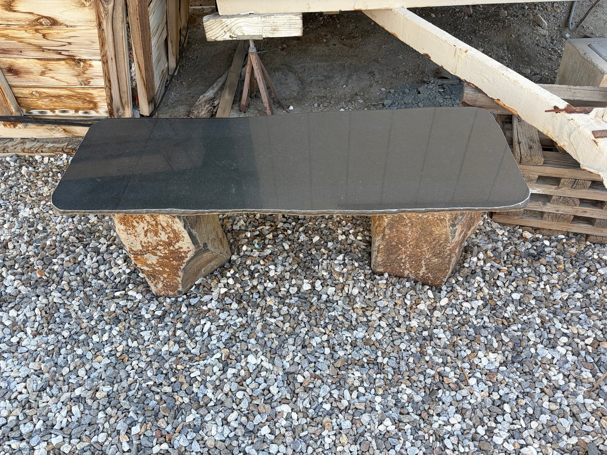 Polished basalt stone garden bench featuring dark natural volcanic stone for modern outdoor landscaping.